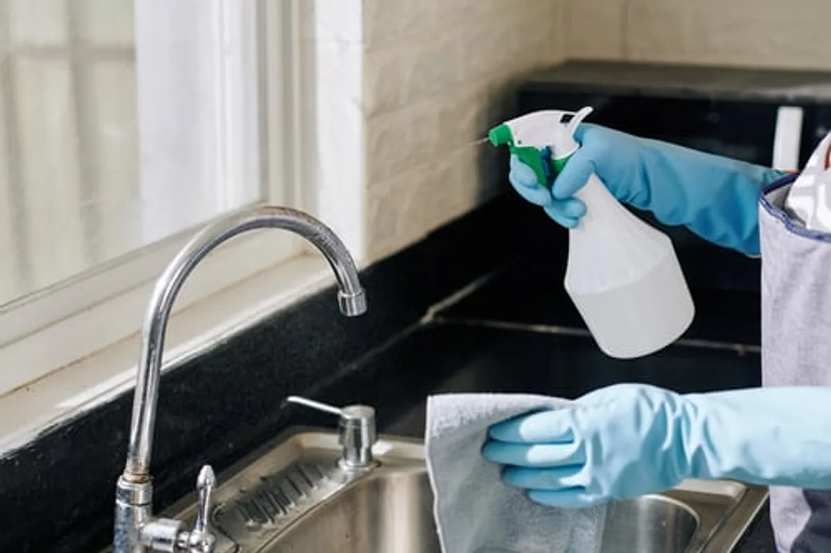 Cleaner disinfecting a dark granite kitchen counter during a deep cleaning service
